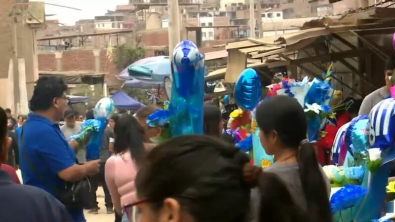 Familia con flores y globos frente a una tumba en el cementerio Nueva Esperanza durante la celebración del Día del Padre