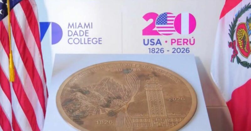 Embajadores Bernie Navarro y Alfredo Ferrero junto a la moneda gigante de cobre durante la ceremonia en la Torre de la Libertad de Miami.