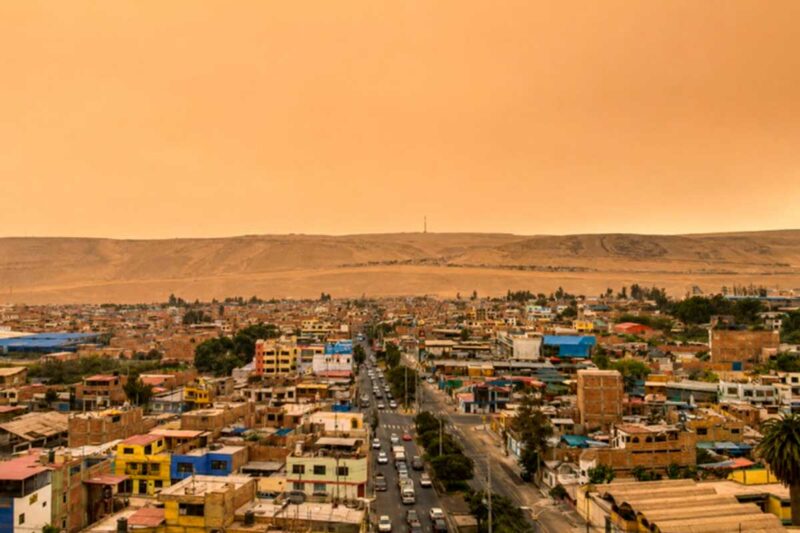 Intensa nube de polvo y arena sobre el balneario de Boca del Río en Tacna, con el cielo de tono amarillento y viviendas afectadas